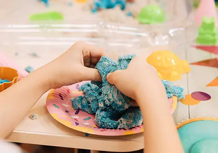 Toddler playing with kenitic sand