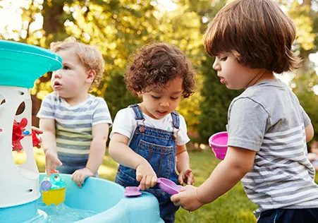 Toddlers playing outside with water toys