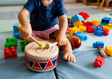 Toddler playing with toy drum